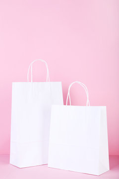 White paper shopping bags on pink background