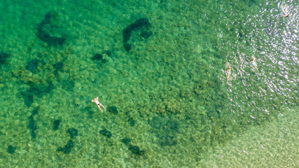 Aerial view of swimming people at sunrise . Mediterranean sea. Transparent water. Top view from flying drone
