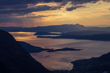 A magnificent sunset scenery over the fjords in Norway in purple tones. Beautiful evening landscape with dramatic sky. Folgefonna national park.