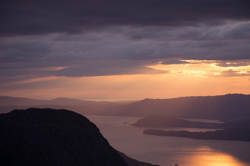A magnificent sunset scenery over the fjords in Norway in purple tones. Beautiful evening landscape with dramatic sky. Folgefonna national park.