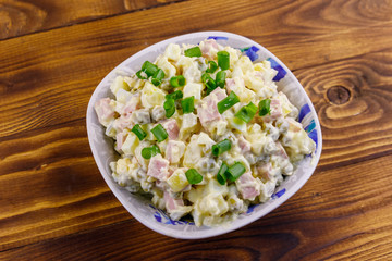Traditional Russian festive salad Olivier on wooden table. Top view