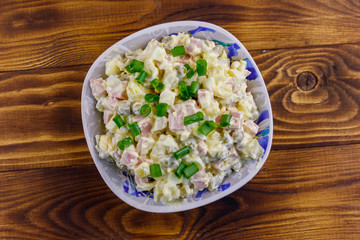 Traditional Russian festive salad Olivier on wooden table. Top view