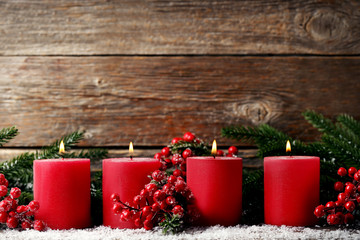 Christmas candles with fir-tree branches and red berries on wooden table