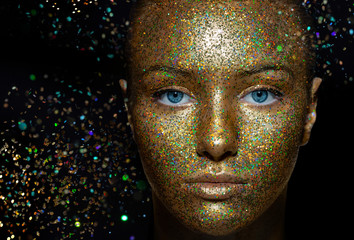 Beautiful girl with artistic make-up and sequins. the beauty of the face.  Close up. Flying particles of glitter. Photos taken in the Studio