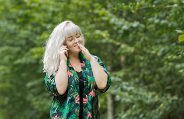 Young beautiful woman, smiling and talking on the mobile phone in the summer park.