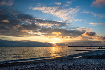 Seascape with beautiful sunset on the background of the coastline.