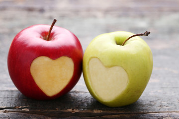 Green and red apple with cutout heart shape on grey wooden table
