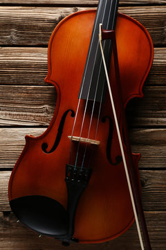 Violin with bow on brown wooden table