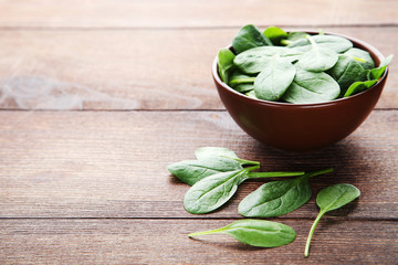 Spinach leafs in bowl on brown wooden table