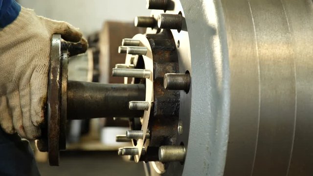 worker puts long metal shaft inside cylindrical truck part