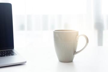 Coffee cup on white tablew with white window in the morning sunlight 