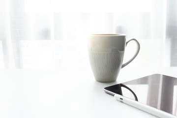 Coffee cup on white tablew with white window in the morning sunlight 