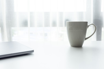 Coffee cup on white tablew with white window in the morning sunlight 