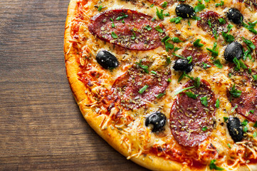 Pizza with Mozzarella cheese, salami, pepper, pepperoni, olives, Spices and Fresh Basil. Italian pizza on wooden background