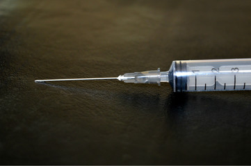 Disposable syringe with needle on black background.
