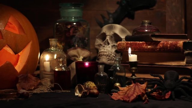 Horrid still life with skull, pumpkin, old books, maple leaves, vintage bottles and candles on witch table. Halloween or esoteric concept. 
