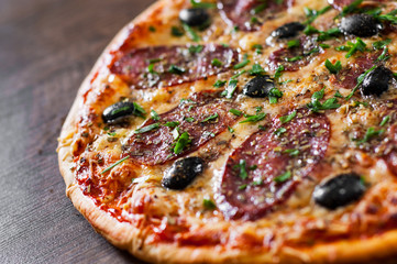 Pizza with Mozzarella cheese, salami, pepper, pepperoni, olives, Spices and Fresh Basil. Italian pizza on wooden background