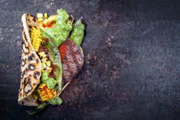Barbecue wagyu hash burger with flatbread, corn and chimichurri sauce as top view on a old metal...