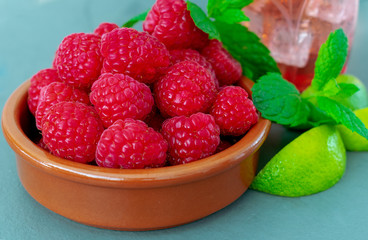 A dish of fresh ripe juicy raspberries, with mint and lime 
