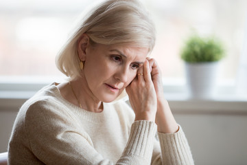 Thoughtful sad mature middle aged woman feeling blue melancholic worried concerned about problems,...