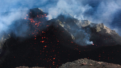 Cratere del vulcano Stromboli ed emissioni di vapore con lava post esplosione e sfondo con mare
