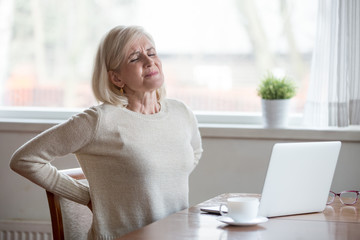 Upset mature middle aged woman feels back pain massaging aching muscles, sad senior older lady...