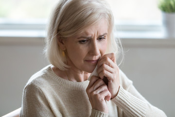 Upset middle aged woman wiping tears crying feeling depressed hopeless lonely after divorce, desperate old senior widow thinking of disease, sorrow or grief, mature elderly lady mourning concept