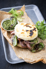 Traditional Columbian arepa con carne desmechada with shredded beef steak and aji criollo as closeup on a backing paper