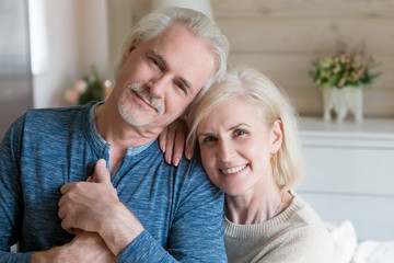 Happy affectionate mature old man and woman embracing looking at camera, middle aged retired...
