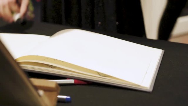 man pastes photograph into book for memories during wedding reception