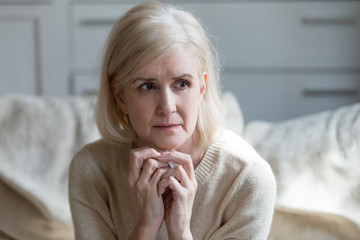 Thoughtful upset mature old lady feeling blue thinking of loneliness or grief, sad middle aged...