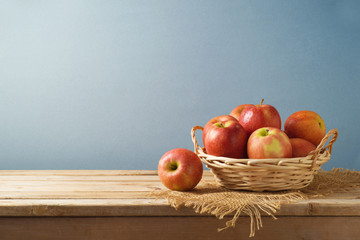 Red apples in basket on wooden kitchen table background