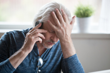 Frustrated older mature retired man feeling upset desperate talking on the phone having problems debt, stressed sad middle aged male depressed by hearing bad news during mobile conversation at home - Powered by Adobe