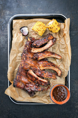 Barbecue spare ribs St Louis cut with hot honey chili marinade and corn as top view in a skillet