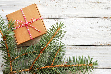 Geschenk und Tannenzweig auf weißem Holz