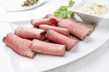 Traditionelle kalte Platte mit aufgeschnittenen Roastbeef und Remoulade als closeup auf einem weissen Teller