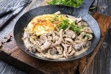 Traditionelles Zürcher Geschnetzeltes mit Rösti als closeup in einer hangeschmiedeten Eisenpfanne