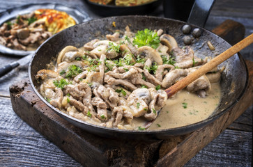 Traditionelles Zürcher Geschnetzeltes mit Rösti als closeup in einer schmiedeeisernen Pfanne
