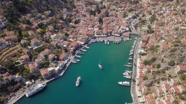 Aerial footage of the beautiful island of Symi (Simi) with Colorful houses and small boats at the heart of the village bay.
