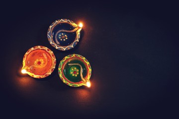Happy Diwali - Colorful Clay Diya lit during Deepavali festival,  selective focus