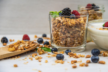 Jars full with granola, yogurt and fresh berries and wood spoon full whit granola, close-up, selective focus