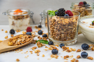 Jars full with granola, yogurt and fresh berries and wood spoon full whit granola, close-up, selective focus
