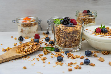 Jars full with granola, yogurt and fresh berries and wood spoon full whit granola, close-up,...