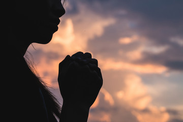 Silhouette off   young woman praying for God's blessings with the power and power of the sacred On...