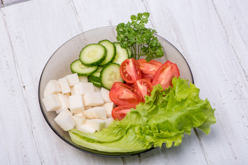 Delicious turnip, cucumber, tomato and parsley ingredients on a vitamin salad on a wooden background