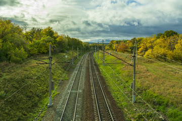 Naklejka na ściany i meble paths of the turning railway in the autumn, among the yellowing trees and the autumn cloudy sky