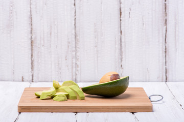 Juicy green avocado chopped on a wooden board on a white background