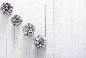 snow painted pine cones on rustic white wood table, Christmas decoration background