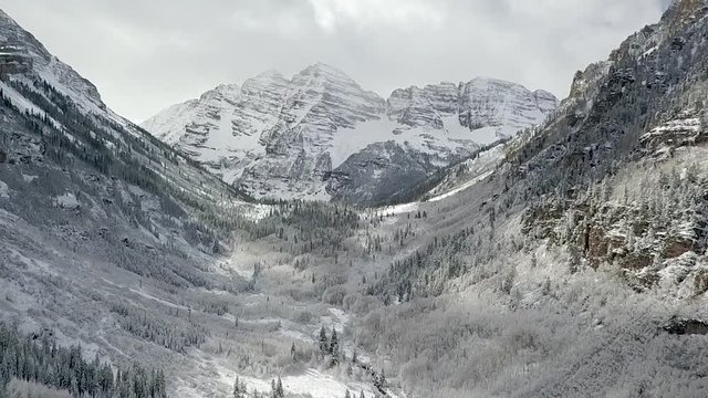 Slow flying aerial view of the Maroon Bells Aspen mountain range in Colorado during winter