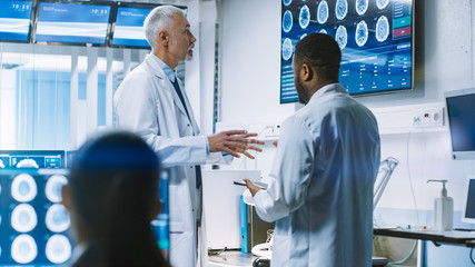 Team of Scientists Work in the Brain Research Laboratory, Discussing Brain Scans Show on Wall TV...